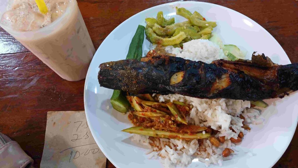 Sepiring Nasi Lemak, Ikan Bakar, Sayuran, dan Segelas es teh tarik di Warung Mamak Chow Kit